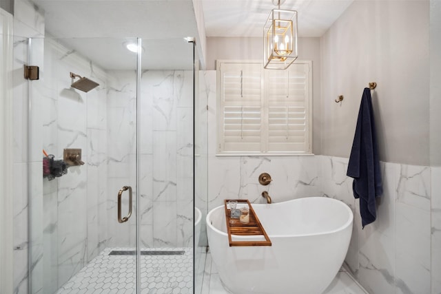 bathroom with a freestanding bath, a marble finish shower, and tile walls