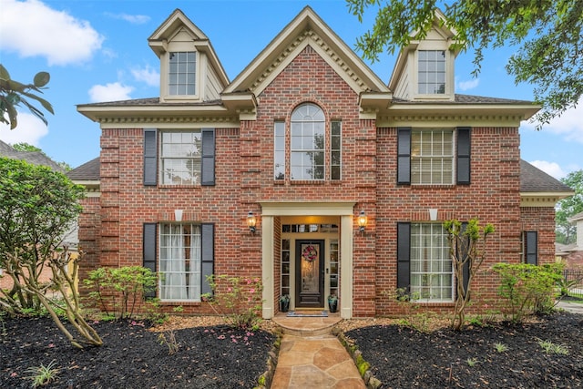 colonial home with a shingled roof and brick siding
