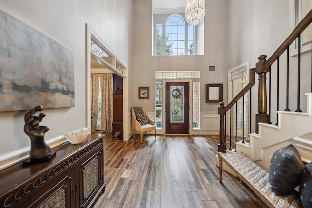 entryway with a towering ceiling, visible vents, dark wood-type flooring, and stairway