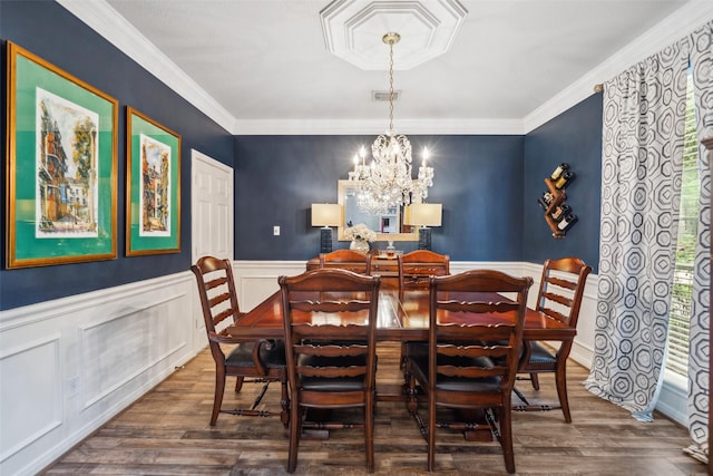 dining area with an inviting chandelier, crown molding, wood finished floors, and visible vents