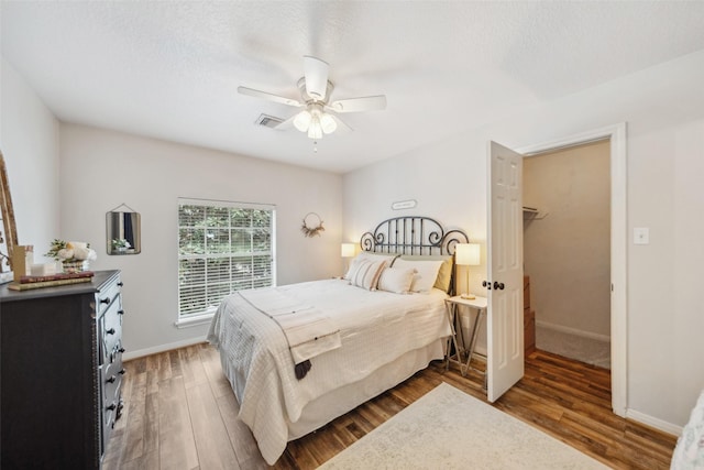 bedroom featuring baseboards, wood finished floors, visible vents, and ceiling fan