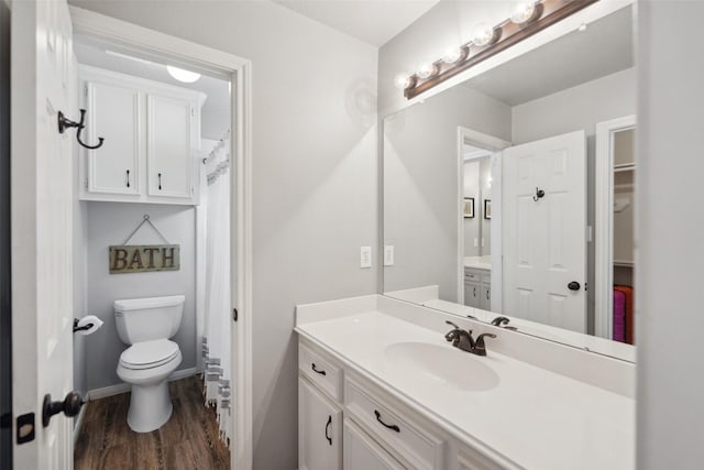 full bathroom featuring baseboards, wood finished floors, vanity, and toilet