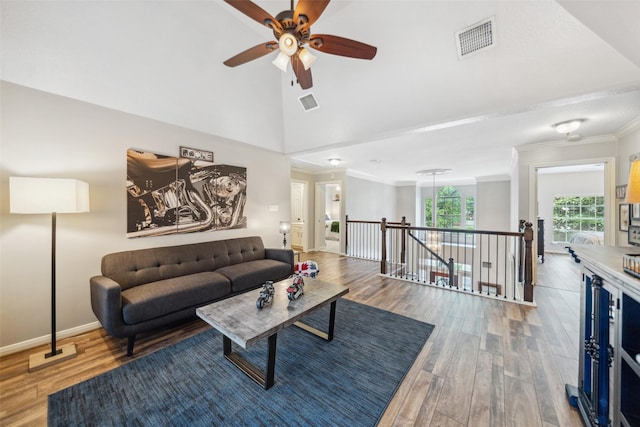 living area with ceiling fan, wood finished floors, visible vents, and ornamental molding