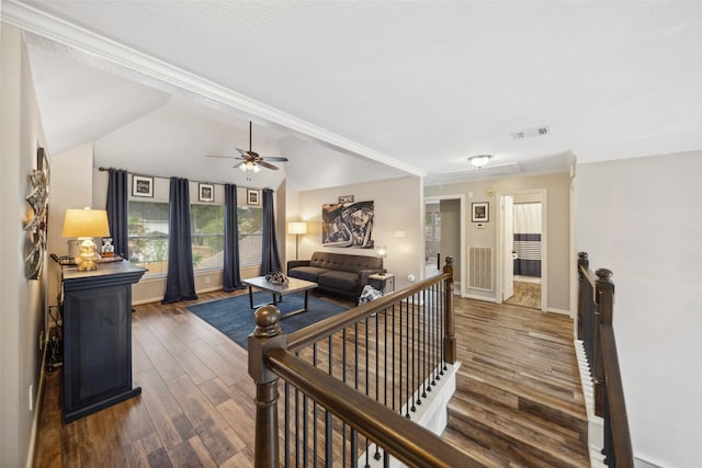 living area featuring wood finished floors, visible vents, a ceiling fan, ornamental molding, and baseboards