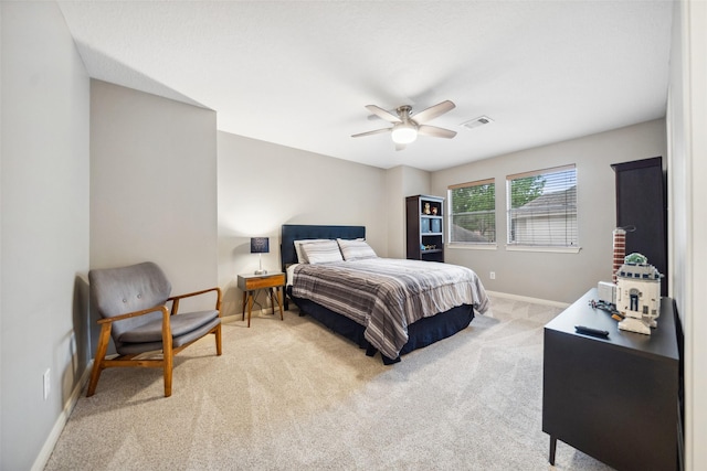 bedroom with baseboards, visible vents, light colored carpet, and ceiling fan
