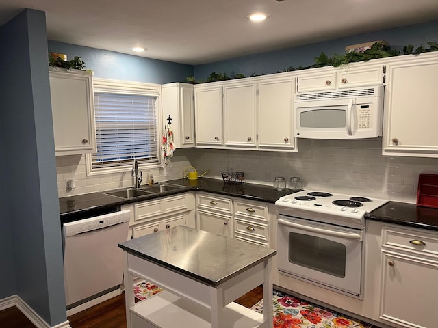 kitchen with white cabinetry, dark countertops, a sink, and white appliances