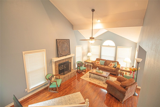 living room with a tile fireplace, vaulted ceiling, wood finished floors, baseboards, and ceiling fan