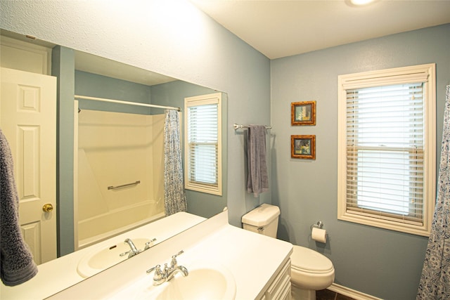 bathroom with baseboards, plenty of natural light, toilet, and vanity