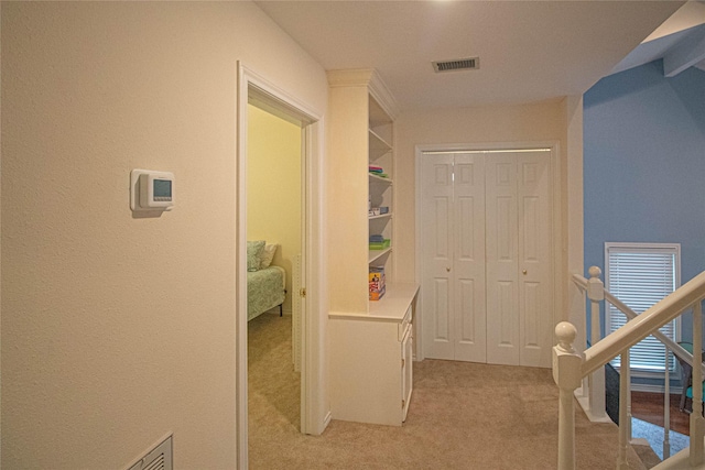 hall with visible vents and light carpet