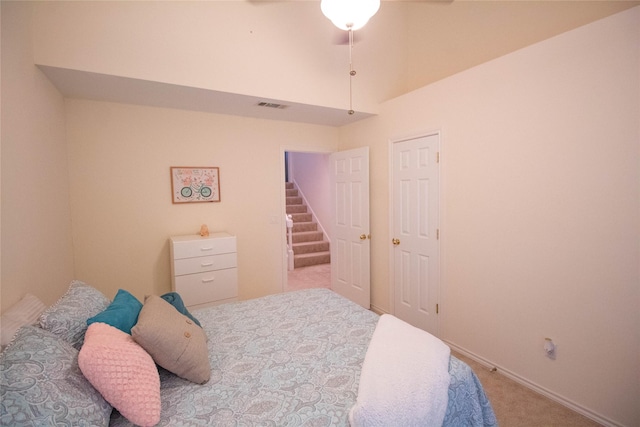 carpeted bedroom with a ceiling fan, visible vents, and vaulted ceiling