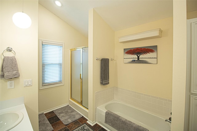 bathroom featuring vaulted ceiling, stone finish flooring, a shower stall, a garden tub, and vanity