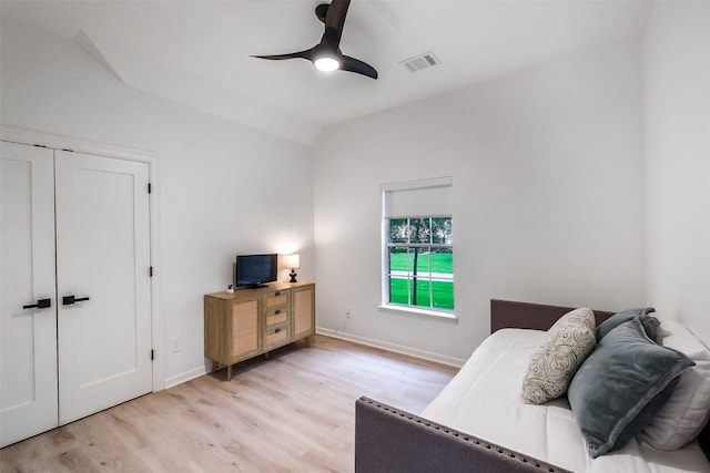 bedroom featuring visible vents, light wood-style floors, a ceiling fan, baseboards, and vaulted ceiling