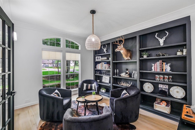 living area with built in features, baseboards, ornamental molding, and wood finished floors