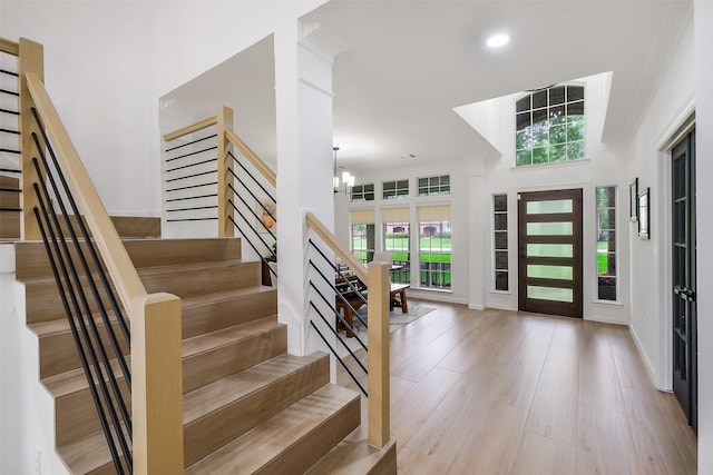 entrance foyer with ornamental molding, a healthy amount of sunlight, and stairway