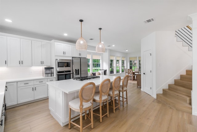 kitchen featuring a kitchen island, visible vents, stainless steel appliances, recessed lighting, and white cabinetry