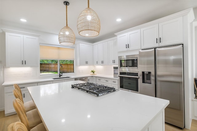 kitchen with a sink, appliances with stainless steel finishes, white cabinetry, and light countertops