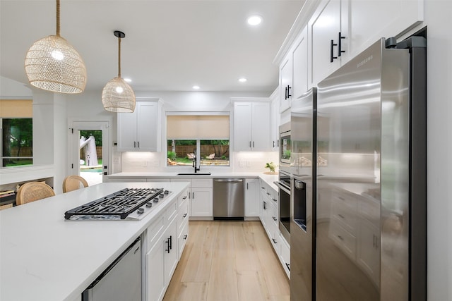 kitchen featuring appliances with stainless steel finishes, a sink, light countertops, recessed lighting, and white cabinetry