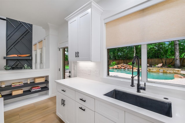 kitchen featuring light wood-style floors, a sink, white cabinets, and light countertops