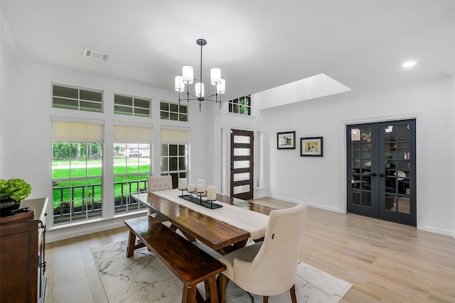 dining area featuring french doors, visible vents, crown molding, an inviting chandelier, and light wood-style flooring