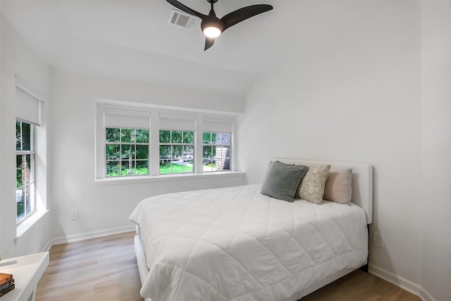 bedroom featuring ceiling fan, visible vents, wood finished floors, baseboards, and lofted ceiling