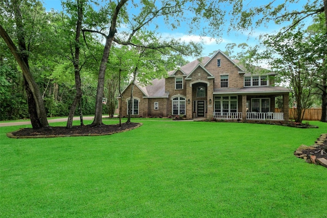 view of front of property featuring brick siding, fence, a front yard, and a porch