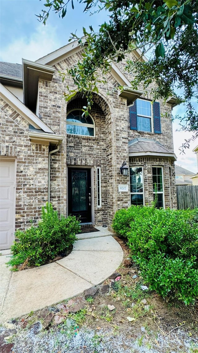 view of exterior entry with fence, an attached garage, and stone siding