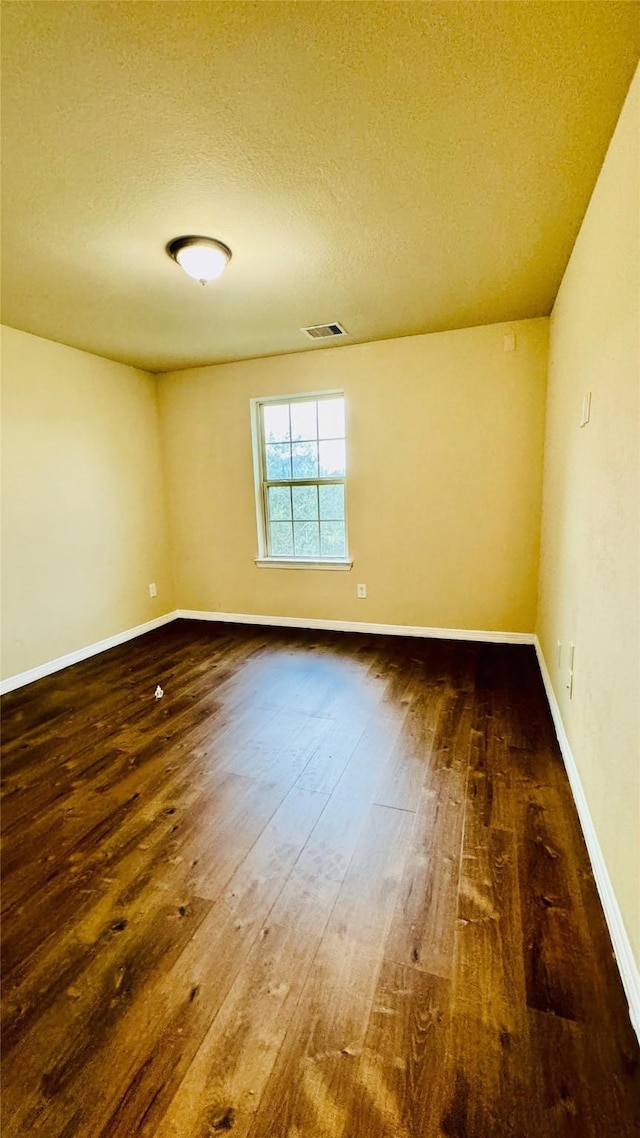 unfurnished room featuring visible vents, baseboards, a textured ceiling, and wood-type flooring