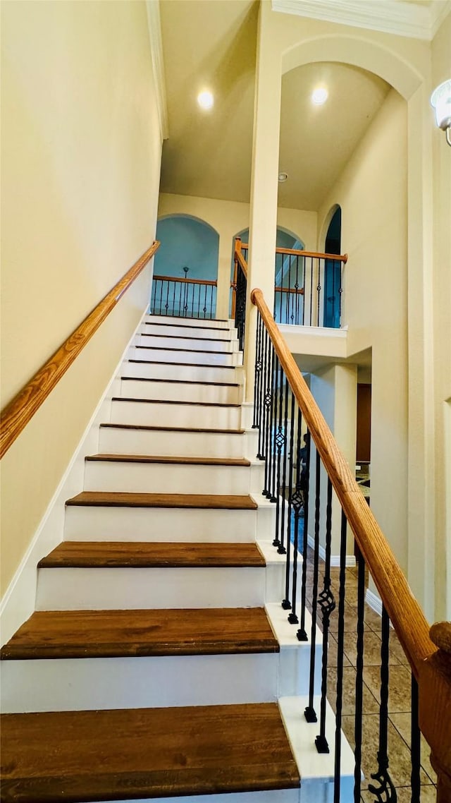 stairway with a high ceiling, ornamental molding, and recessed lighting