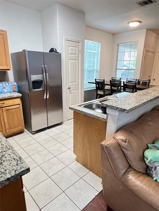 6022 Yorkglen Manor Ln, Houston, TX 77084 - kitchen with stainless steel fridge, light tile patterned floors, and a kitchen breakfast bar