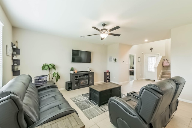 living area featuring ceiling fan, baseboards, stairway, and light tile patterned flooring