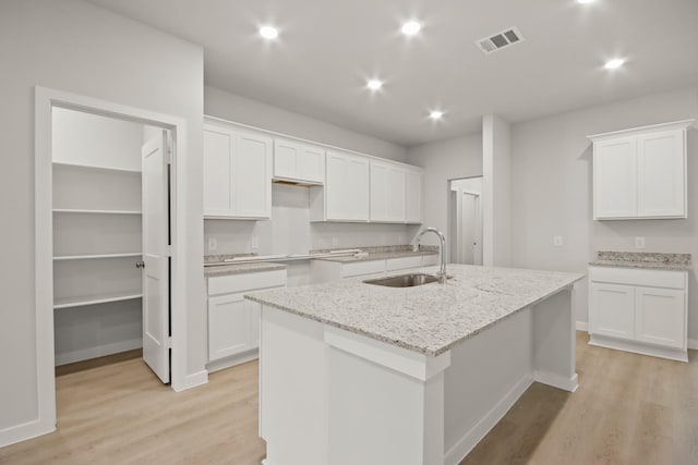17832 Lionheart Rd, Conroe, TX 77306 - kitchen featuring a sink, light wood-style flooring, a center island with sink, white cabinets, and recessed lighting