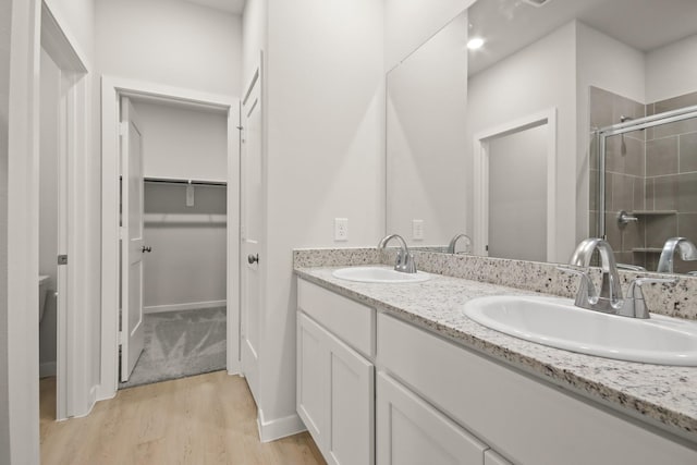 17832 Lionheart Rd, Conroe, TX 77306 - bathroom with double vanity, wood finished floors, a shower stall, and a spacious closet