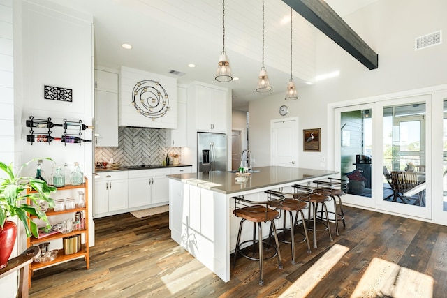 kitchen featuring stainless steel fridge with ice dispenser, visible vents, a kitchen bar, tasteful backsplash, and dark wood-style flooring