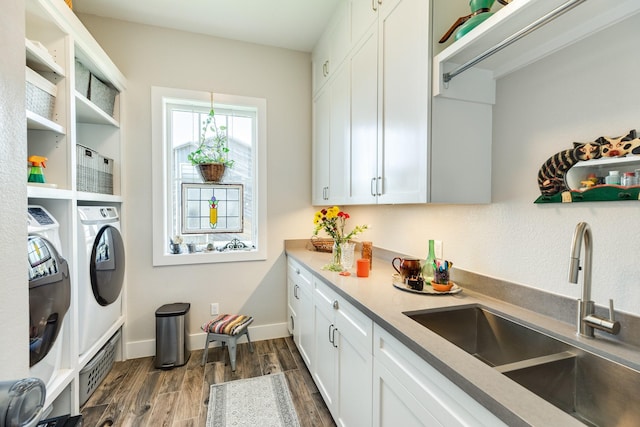 clothes washing area featuring a sink, independent washer and dryer, baseboards, cabinet space, and dark wood-style flooring
