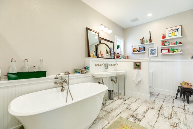 bathroom with wainscoting, wood finished floors, and a freestanding tub