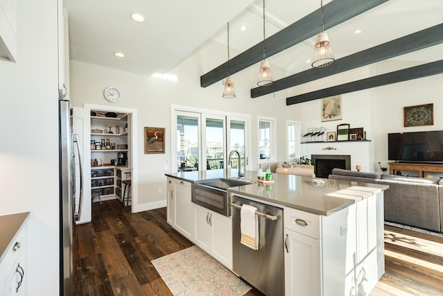kitchen with dishwasher, white cabinets, open floor plan, and a sink