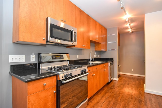 915 Franklin St Unit 4A, Houston, TX 77002 - kitchen featuring stainless steel appliances, rail lighting, a sink, dark wood-style flooring, and baseboards