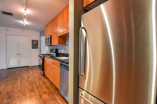 915 Franklin St Unit 4A, Houston, TX 77002 - kitchen featuring stainless steel appliances, a sink, track lighting, dark countertops, and dark wood-style floors