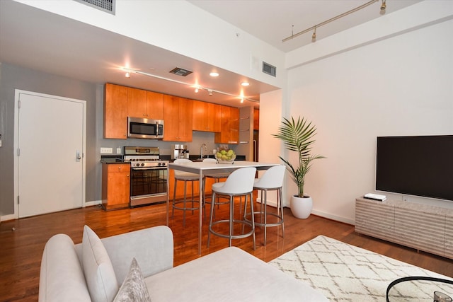 915 Franklin St Unit 4A, Houston, TX 77002 - kitchen with white gas range oven, track lighting, stainless steel microwave, a breakfast bar area, and dark wood-style floors