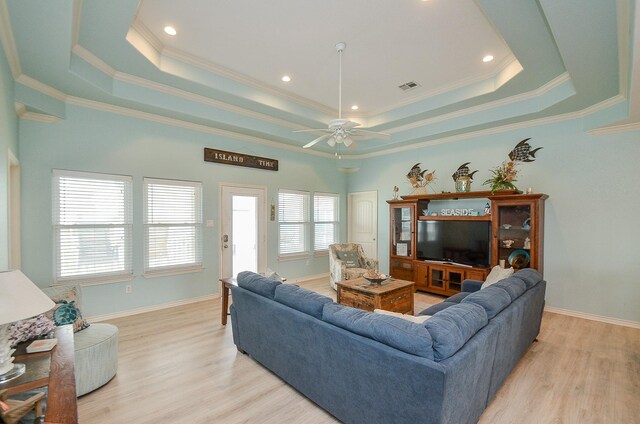 3346 Pirates Cv, Crystal Beach, TX 77650 - living room with a ceiling fan, a tray ceiling, light wood-style flooring, ornamental molding, and visible vents