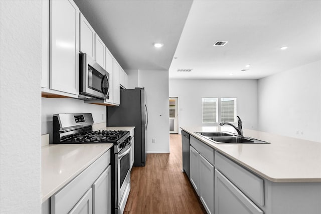 kitchen featuring dark wood-style flooring, stainless steel appliances, visible vents, and a sink