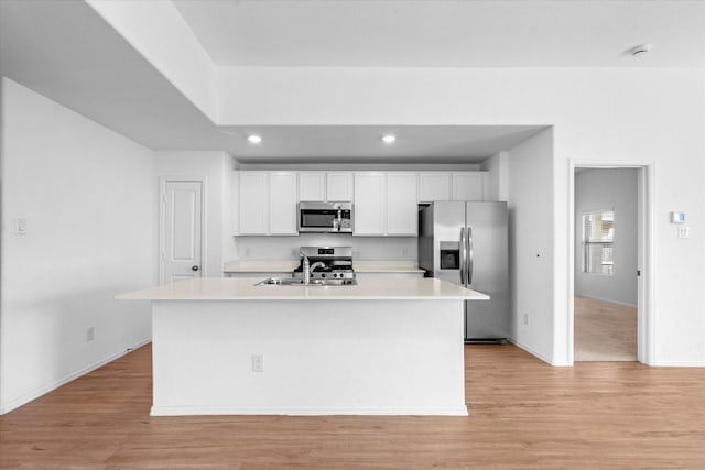 kitchen with white cabinets, light wood-style flooring, a sink, and appliances with stainless steel finishes