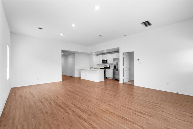 unfurnished living room with light wood-type flooring, baseboards, visible vents, and recessed lighting