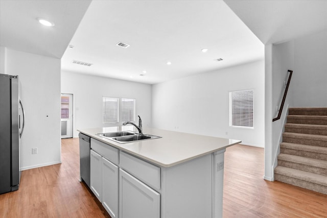 kitchen with stainless steel appliances, light countertops, visible vents, a sink, and light wood-style flooring