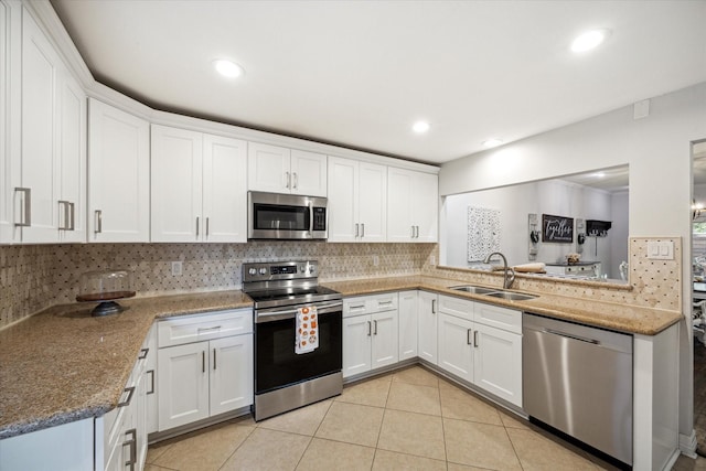 12692 Briar Patch Rd, Houston, TX 77077 - kitchen featuring stainless steel appliances, backsplash, light tile patterned floors, a sink, and white cabinetry