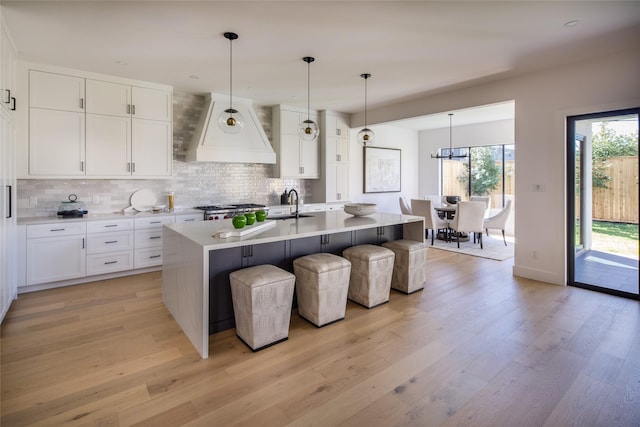 2239 Colquitt St, Houston, TX 77098 - kitchen with decorative backsplash, range, a sink, custom exhaust hood, and light wood finished floors