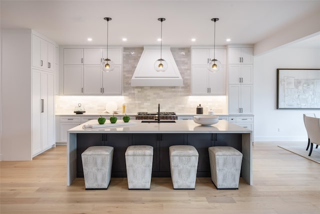 2239 Colquitt St, Houston, TX 77098 - kitchen with custom range hood, light countertops, white cabinetry, and backsplash