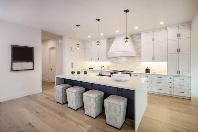 2239 Colquitt St, Houston, TX 77098 - kitchen with baseboards, light wood-style floors, premium range hood, and tasteful backsplash