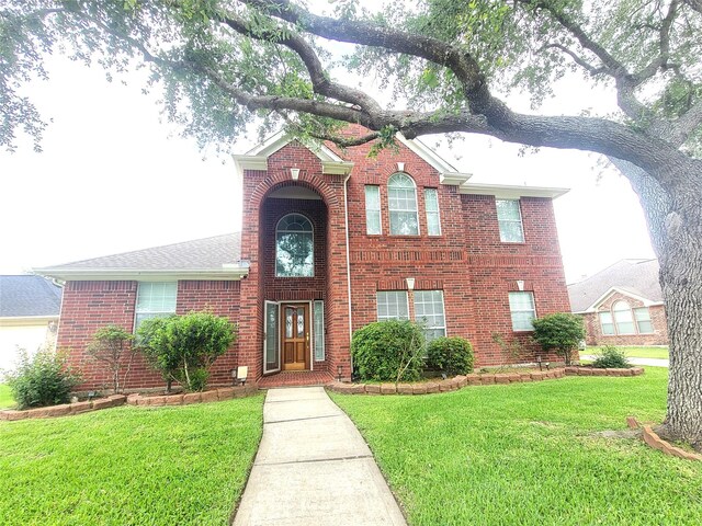traditional-style home featuring a front lawn and brick siding