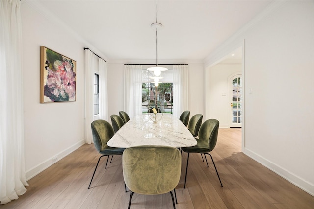dining space with light wood-type flooring, baseboards, and crown molding